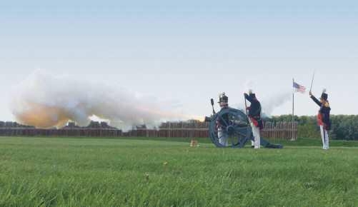 Reenactors fire a cannon.
