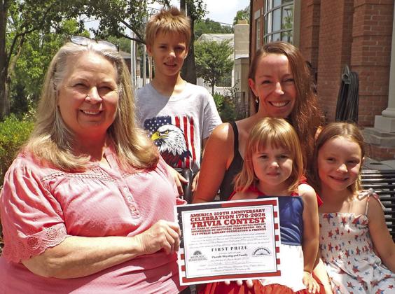 Janel Haas, director of Way Public Library, presenting certificate to the Meysing famliy, who were the first prize winners of the America 250th Anniversary Celebration 1776-2026 Trivia Contest. Family members pictured are Hugo, Pascale, Julia and Louise. First prize was $250.