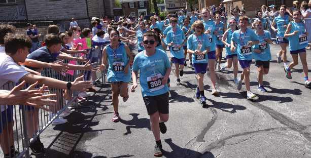Saint Rose seventh and eighth graders run the 5k while classmates cheer them on.