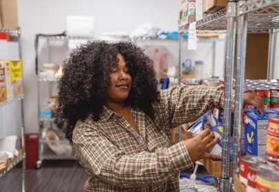 Owens student worker Tamia Hayes stocks the shelves of the Harvest Food Pantry. Photo used with permission from Owens Community College.