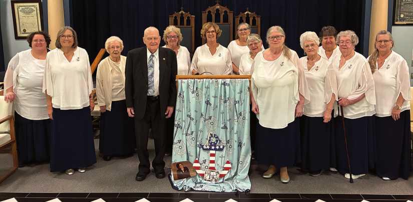 Veterans Ray Curtis, to the left of the podium, and Barb Newman, to the right of the podium, with members of Lotus Chapter surrounding them.