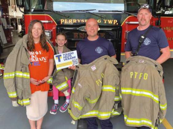Alona Matchenko, president, Toledo Helps Ukraine; her daughter, Jasmine, and Perrysburg Township Firefighter/Paramedics Mike Thompson and Branden Abke, show some of decommissioned turnout gear donated by the Perrysburg Township Fire Department to be shipped to Ukraine by THU.