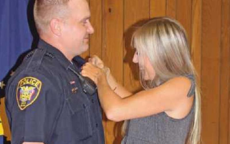 Kelly Okoneski attaches the pin to newly hired Patrol Officer Jared Okoneski during the meeting.