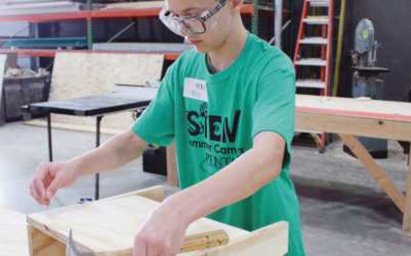 Above left, Henry Halm, a seventh grader, and right, Will Matthews, ninth grade, learn how to build a wooden storage bench as part of advanced STEM activities. Both enjoyed working with wood and utilizing various tools.