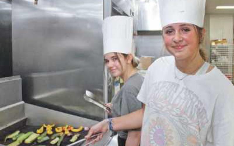 Emme Yonker and Jenna Hogrefe grill vegetables as part of the culinary activities.