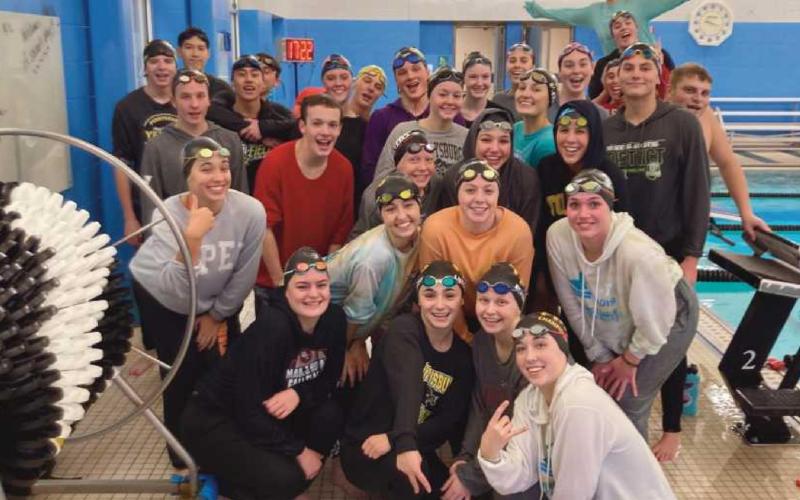 PHS swim team members pose poolside just after swimming in their sweats.