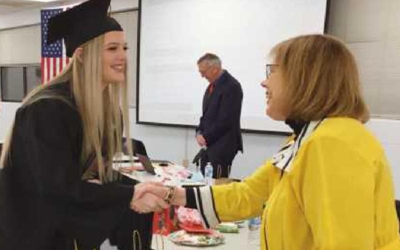 Ava Bockbrader receives a congratulatory handshake from school board member Sue Larimer.