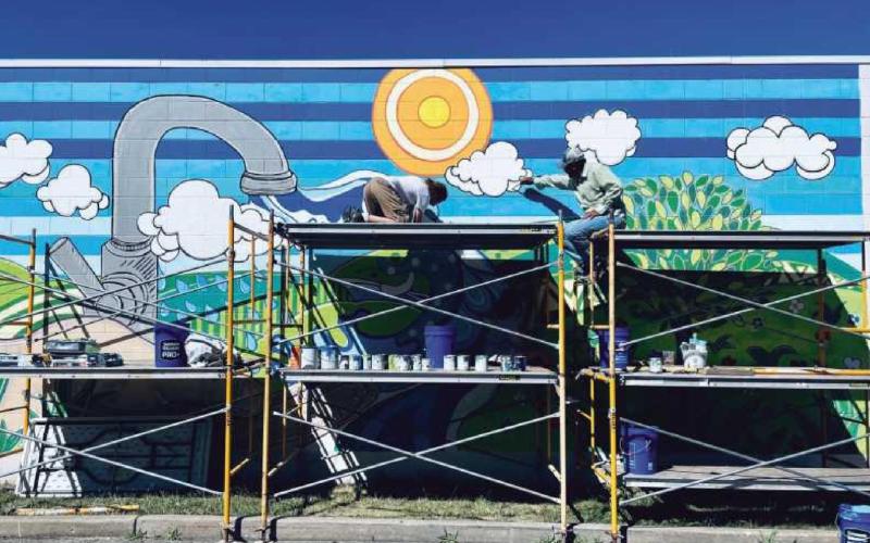 Above is the mural painting in process by artist Terry A. Burton and his team. Mr. Burton is pictured at right. Below is the completed masterpiece at the ribbon-cutting ceremony with, from left: Doug Williams, Maren Tregillis, Amy Siders, Scott Williams, Julie Williams and Jessica Jacobs.
