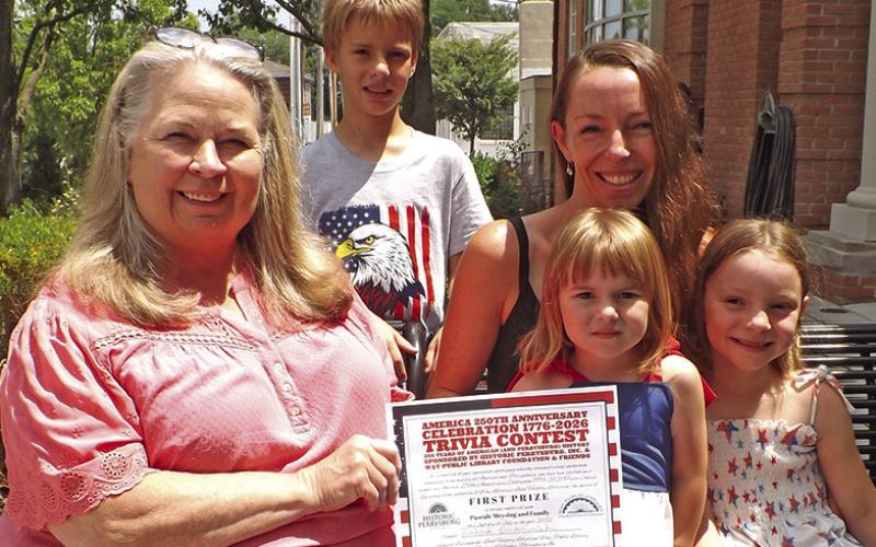 Janel Haas, director of Way Public Library, presenting certificate to the Meysing famliy, who were the first prize winners of the America 250th Anniversary Celebration 1776-2026 Trivia Contest. Family members pictured are Hugo, Pascale, Julia and Louise. First prize was $250.