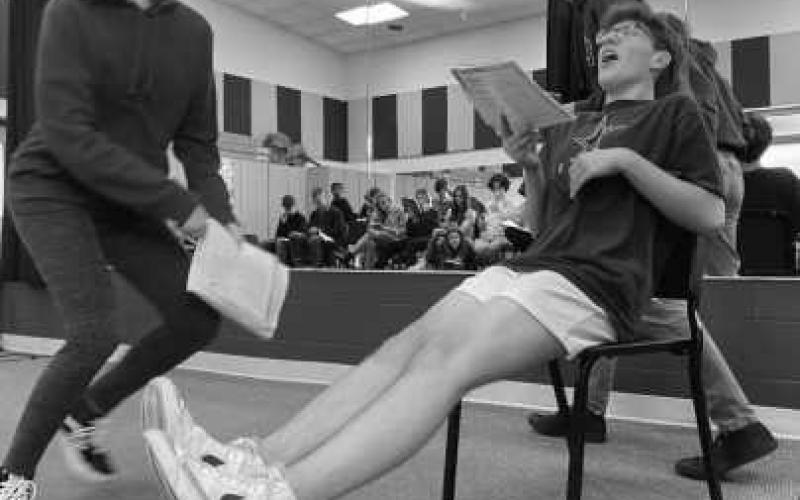 Actors Jessica Zsenyuk, Evan Boyers and Seth Ermie rehearse a scene while other actors prepare off stage.