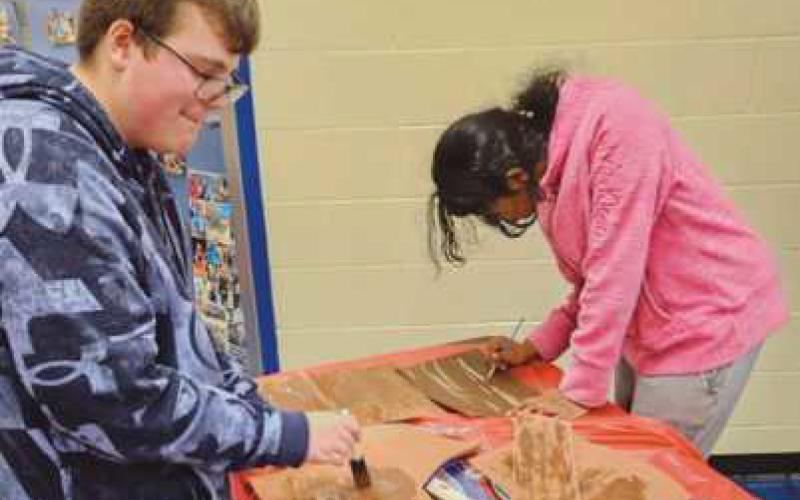 Drama Club members Jake Moon and Harshini Kanumilli paint items for the display case for the upcoming show.