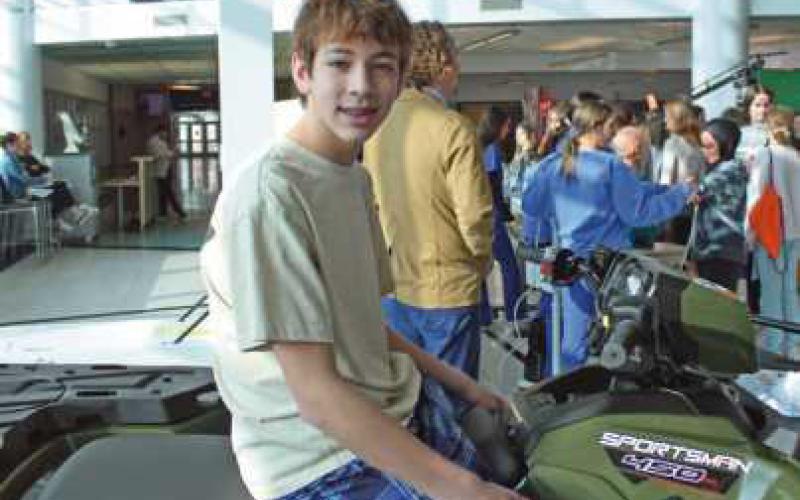 Landon Kobylak jumps on an all-terrain vehicle on display at the power sports and engine systems program.