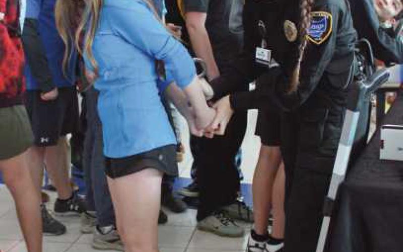 Peyton Jagodzinski is handcuffed by a public safety student, who demonstrates how the cuffs function.