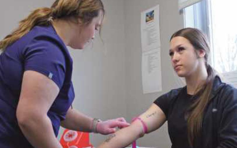 Senior phlebotomy students practice on each other. Hannah Guercio, left, finds a vein before drawing blood from classmate Bella Spellis.
