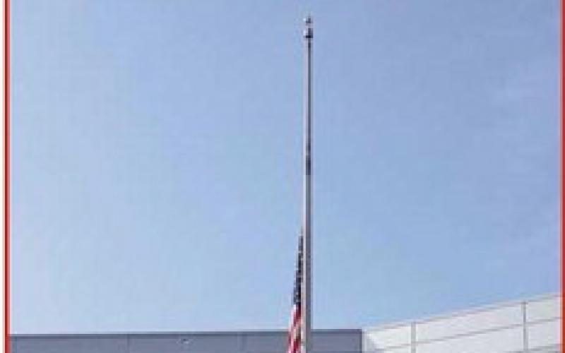 As the flag is lowered to half-staff, one of several planes–provided by the Experimental Aircraft Association– flies over the ceremony dipping its wings.