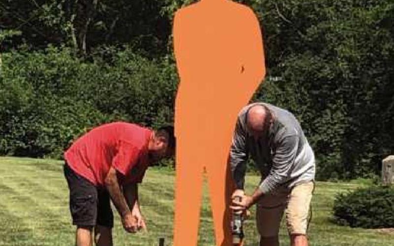 Top photo, the Man in the City sculpture installed on a rooftop in downtown Perrysburg. Bottom, Rick Szydlowski, left, and artist John Sauve’ install the 10-foot Man in the City sculpture at a park.