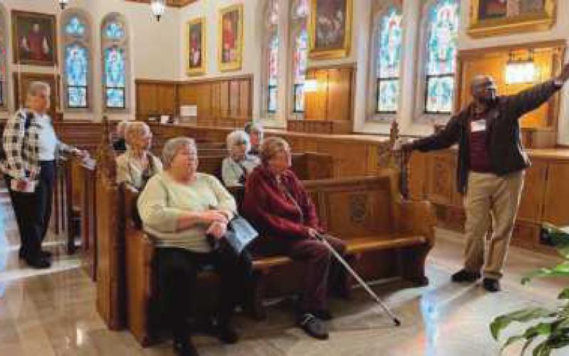 Abimbola Fajobi points out the historical features of the cathedral. Below are, from left, Kathy Helmick, Pat Jacobsen, Sue Stevenson, Dee Kroger, Joanne West, Doris Currie and Mr. Fajobi.