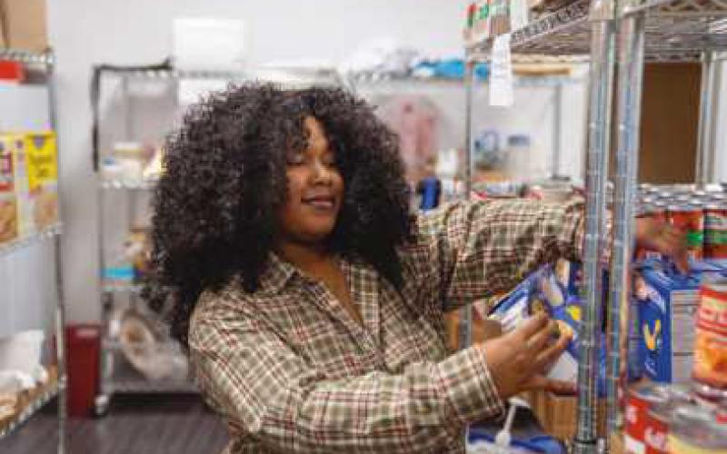 Owens student worker Tamia Hayes stocks the shelves of the Harvest Food Pantry. Photo used with permission from Owens Community College.