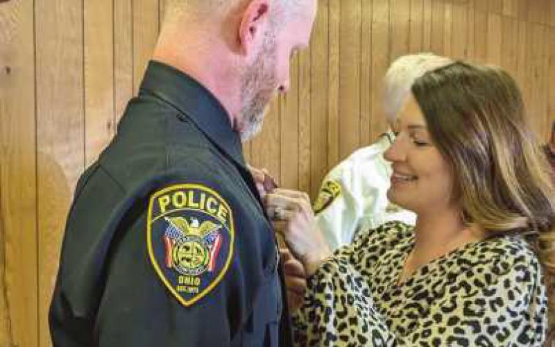 Pinning his new sergeant designation on the uniform is Mrs. Glass.