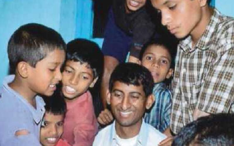 Father Kishore Kottana, of St. Rose Catholic Church, center, is surrounded by boys who live in the home in Sirsi, India.