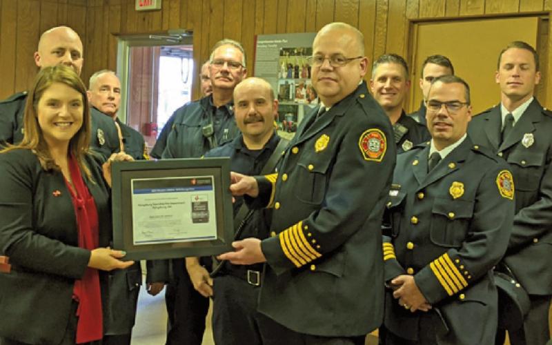 Sara Hegarty, American Heart Association executive director, presents the lifeline award to Fire Chief Tom Brice and Deputy Chief Jim Rodriguez as members of the department watch.