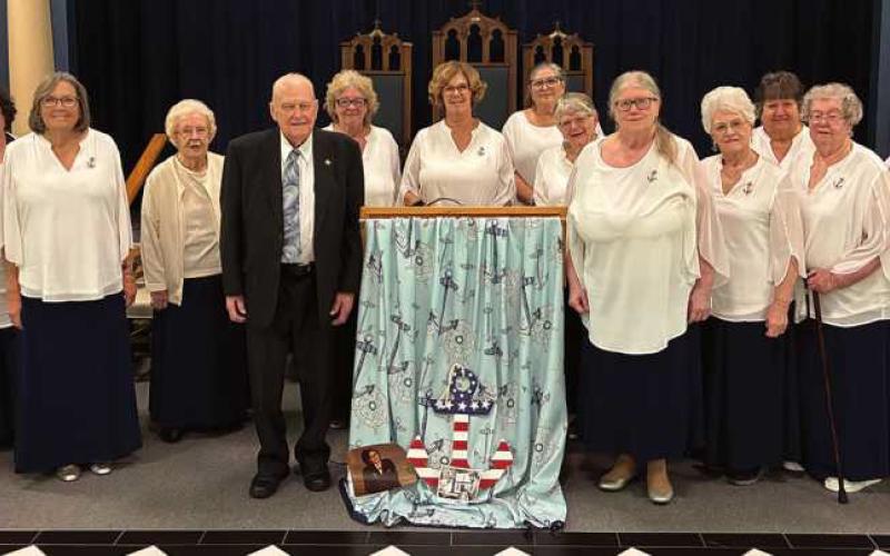 Veterans Ray Curtis, to the left of the podium, and Barb Newman, to the right of the podium, with members of Lotus Chapter surrounding them.