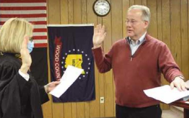 To open the January 5 meeting, Wood County Common Pleas Judge Molly Mack administered the oath of office to newly re-elected trustees Bob Mack, above, her husband, and to Gary Britten, below, whose wife Becky is holding the Bible.