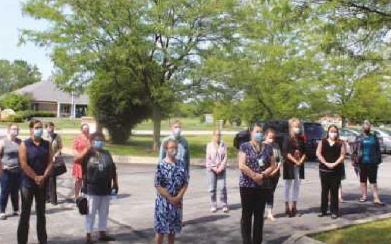 Above, left, Barb Futrell, nursing supervisor for A Renewed Mind, writes her late niece’s name on a purple flag as part of the International Overdose Awareness Day event hosted by the behavioral health center at their Perrysburg headquarters; above, right, a chalk message written by one of the participants; and bottom, right, a group gathers to hear the speakers.