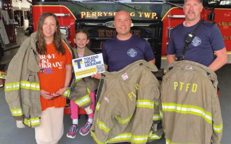Alona Matchenko, president, Toledo Helps Ukraine; her daughter, Jasmine, and Perrysburg Township Firefighter/Paramedics Mike Thompson and Branden Abke, show some of decommissioned turnout gear donated by the Perrysburg Township Fire Department to be shipped to Ukraine by THU.