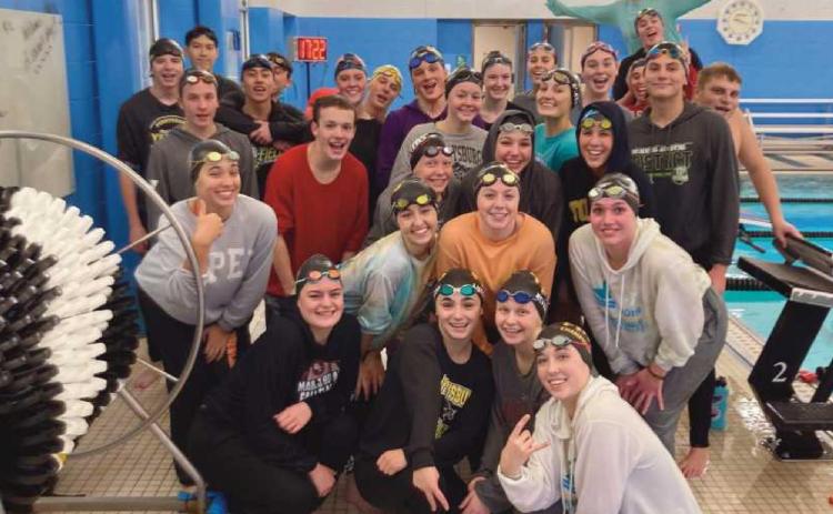 PHS swim team members pose poolside just after swimming in their sweats.