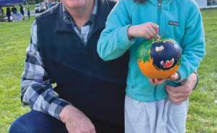 Lena Coulson, pictured with her grandfather and Perrysburg Rotarian Mark Weber, displays her painted pumpkin.