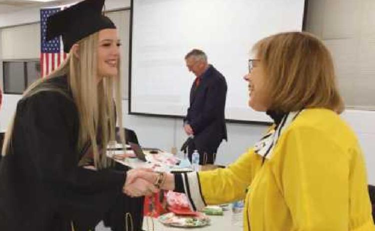 Ava Bockbrader receives a congratulatory handshake from school board member Sue Larimer.