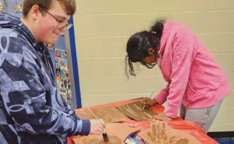 Drama Club members Jake Moon and Harshini Kanumilli paint items for the display case for the upcoming show.