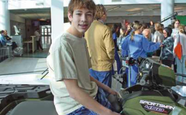 Landon Kobylak jumps on an all-terrain vehicle on display at the power sports and engine systems program.