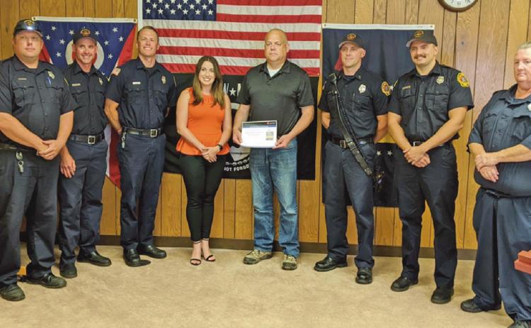 Elizabeth Lewis, center, presents Fire Chief Tom Brice with the AHA award.