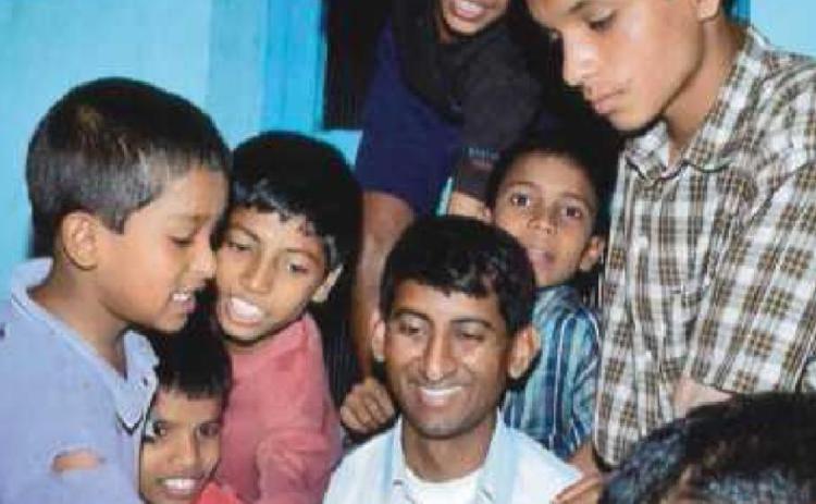 Father Kishore Kottana, of St. Rose Catholic Church, center, is surrounded by boys who live in the home in Sirsi, India.