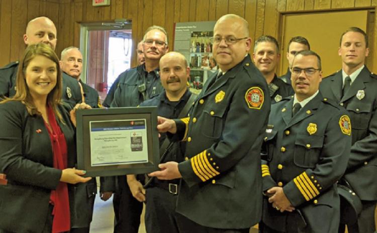 Sara Hegarty, American Heart Association executive director, presents the lifeline award to Fire Chief Tom Brice and Deputy Chief Jim Rodriguez as members of the department watch.