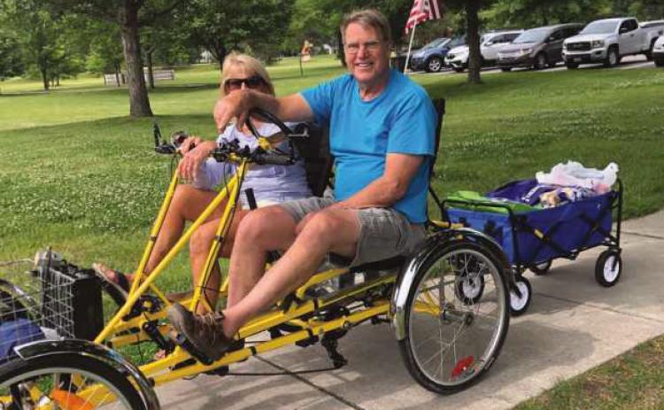 Charlie Gries, founder and coordinator of Perrysburg Slow Rollers, and partner Cathy Gries heading to Wednesday at Woodlands lunchtime concert series with a cart full of food to serve free hotdog lunches to audience members.